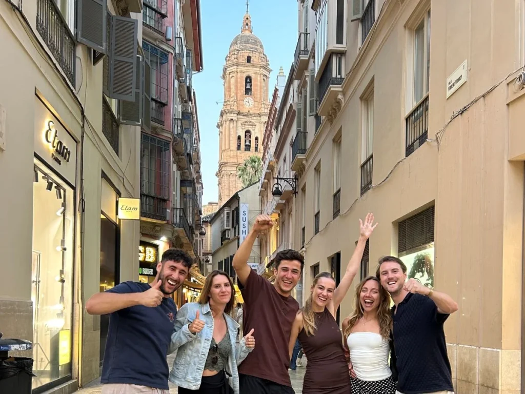 Free walking tour group in Calle Larios with the Cathedral of Malaga in the background having a great time with a local guide