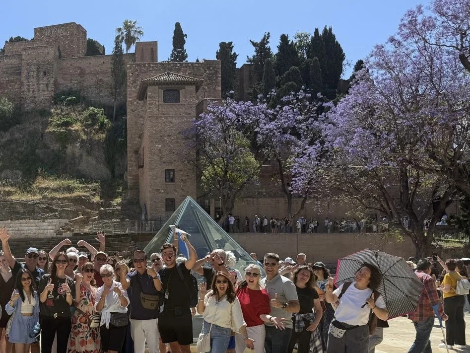 Group of tourists during a guided free tour in Malaga with the alcazaba and roman theatre in background