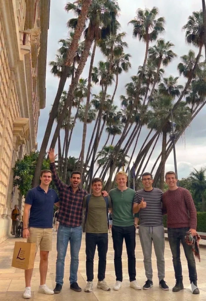 Five tourists with tour guide after a private tour in Málaga historical centre next to the museum with palm trees in the background