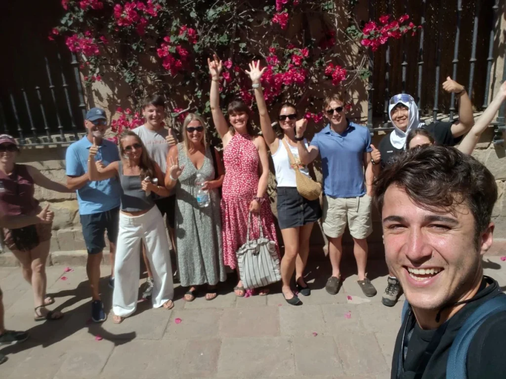Customised private tour group and the local tour guide having fun in the old town of Málaga with red flowers in the background