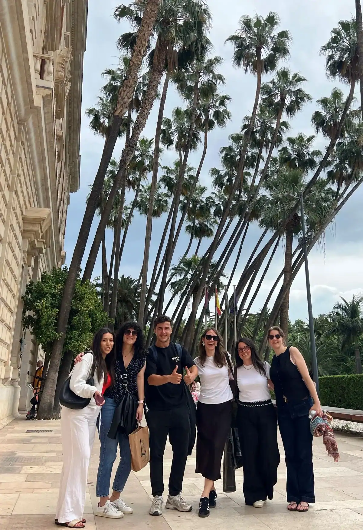 Customised private tour group with local guide having fun in front of the museum of Málaga with palm trees in the background after a tour through Málaga's old historic centre