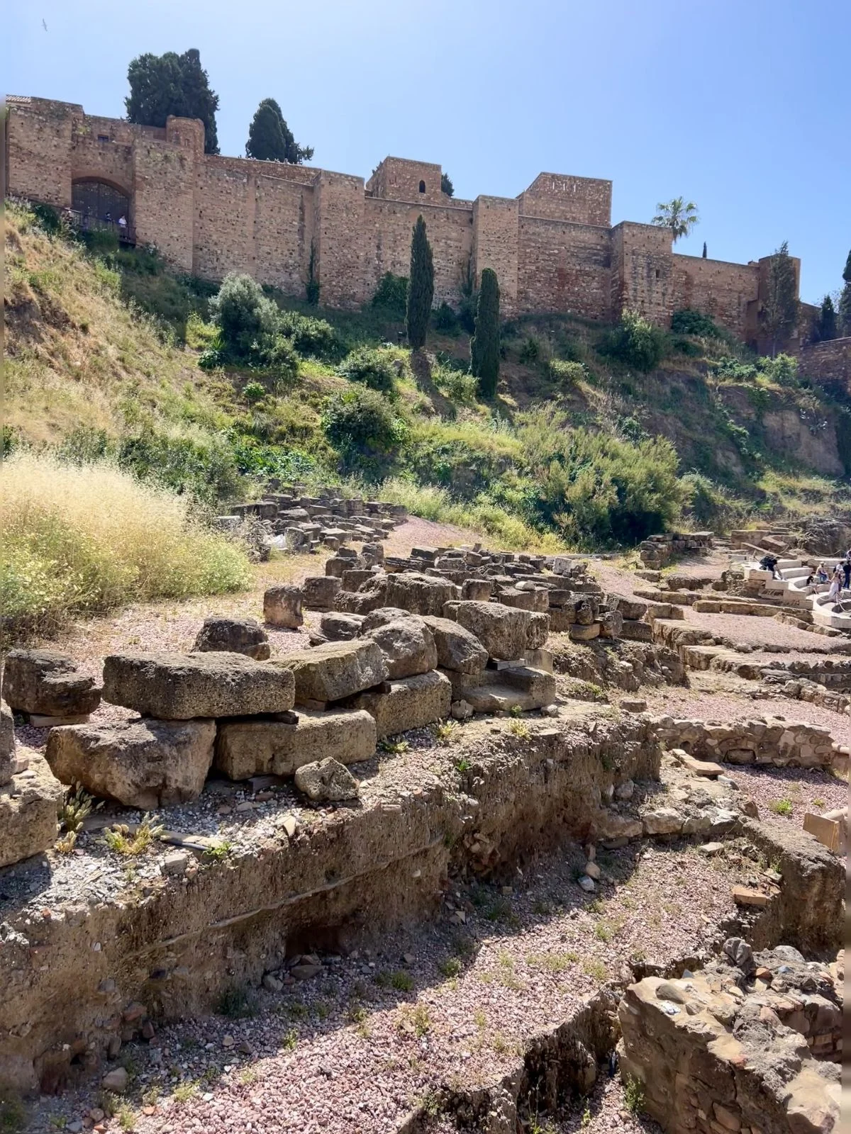 dicover the ruins and monuments of the roman theatre and alcazaba on top with blue sky during a free tour in malaga historic centre