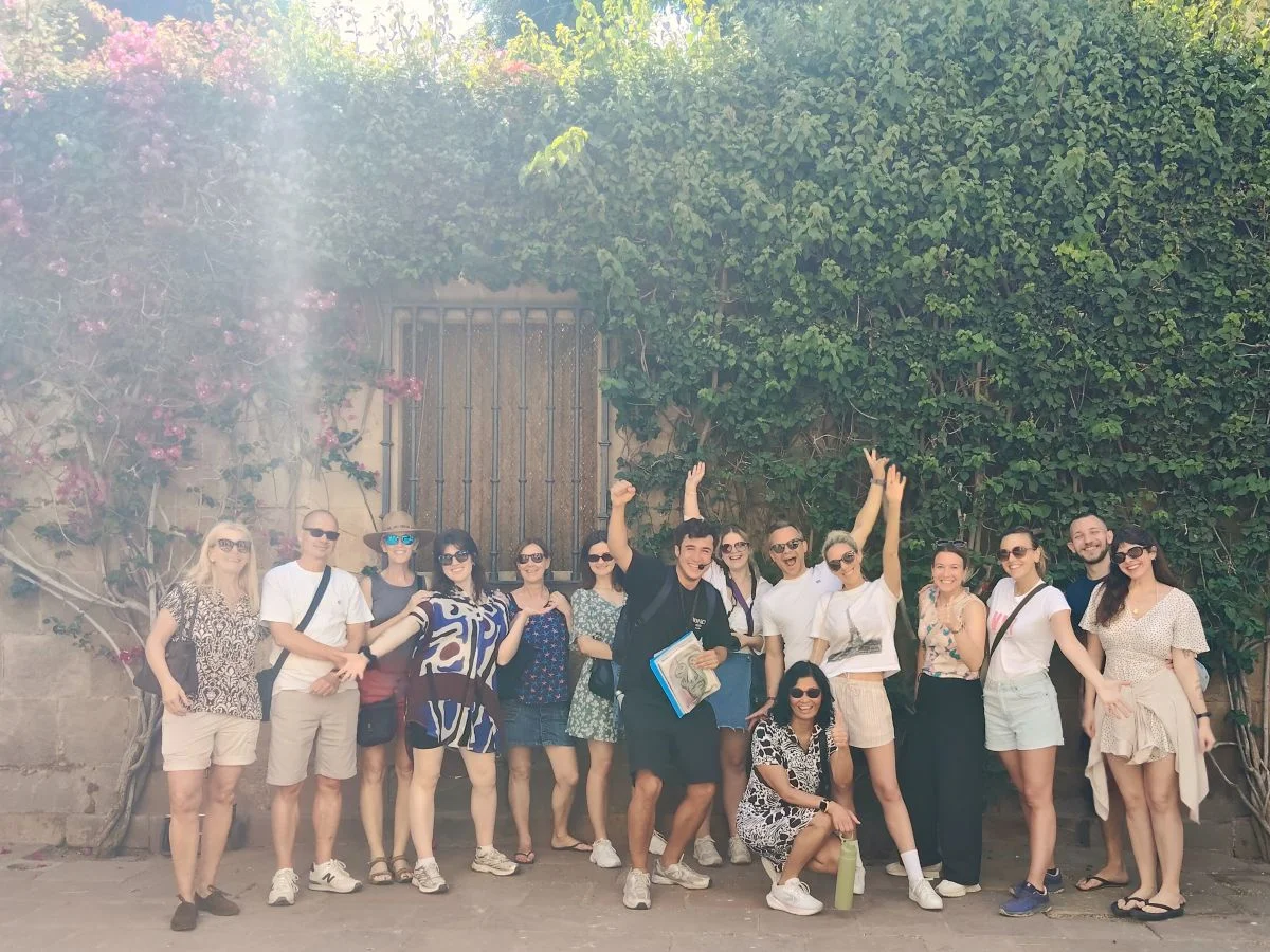 Group of tourists with local guide enjoying the city during free walking tour of malaga historic centre with monuments and plants in background next to the picasso museum