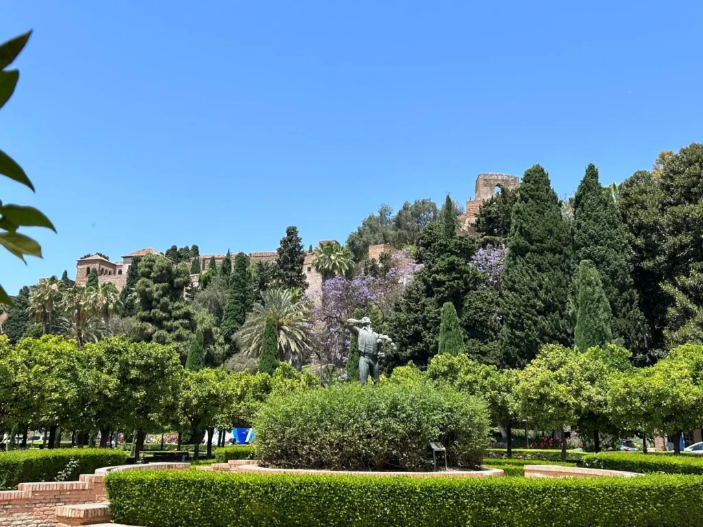 Formal Mediterranean gardens of Jardines de Pedro Luis Alonso in Málaga with fountain lily pond and Alcazaba walls in the background
