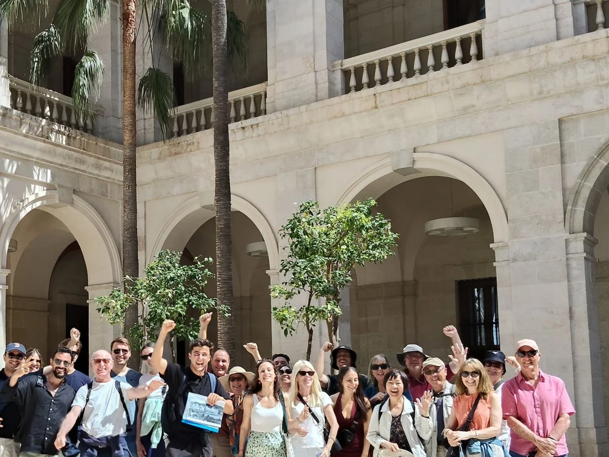Free tour group having fun with tour guide in the patio of museum de malaga with palm trees and orange trees in background