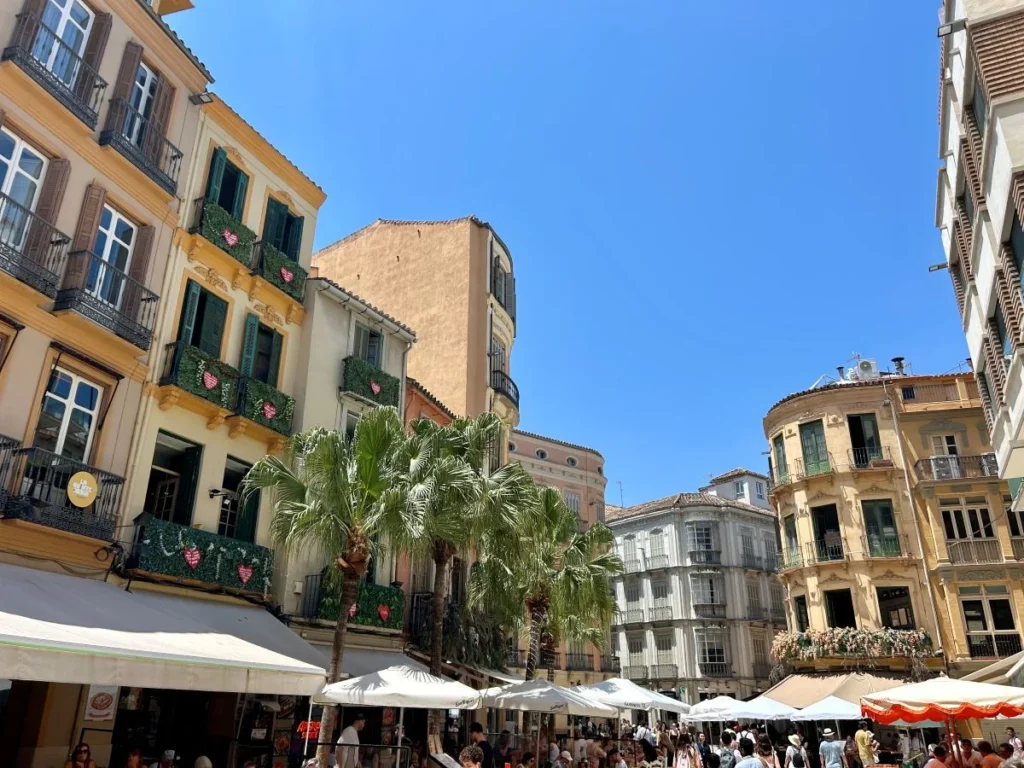 Narrow cobbled street in Málaga historic centre with traditional whitewashed buildings and orange trees