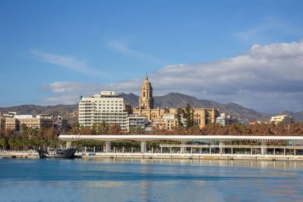 Muelle Uno harbour promenade in Málaga with the cathedral and Mediterranean sea and mountains on a sunny day