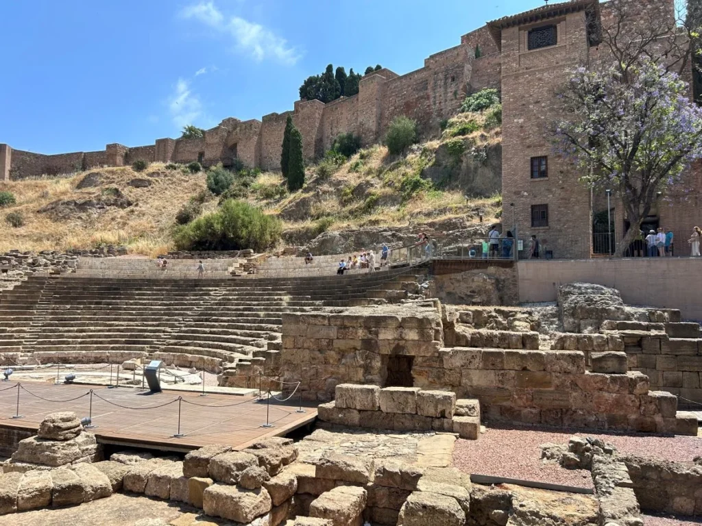 Ancient Roman theatre ruins in Málaga with the Alcazaba fortress rising behind them