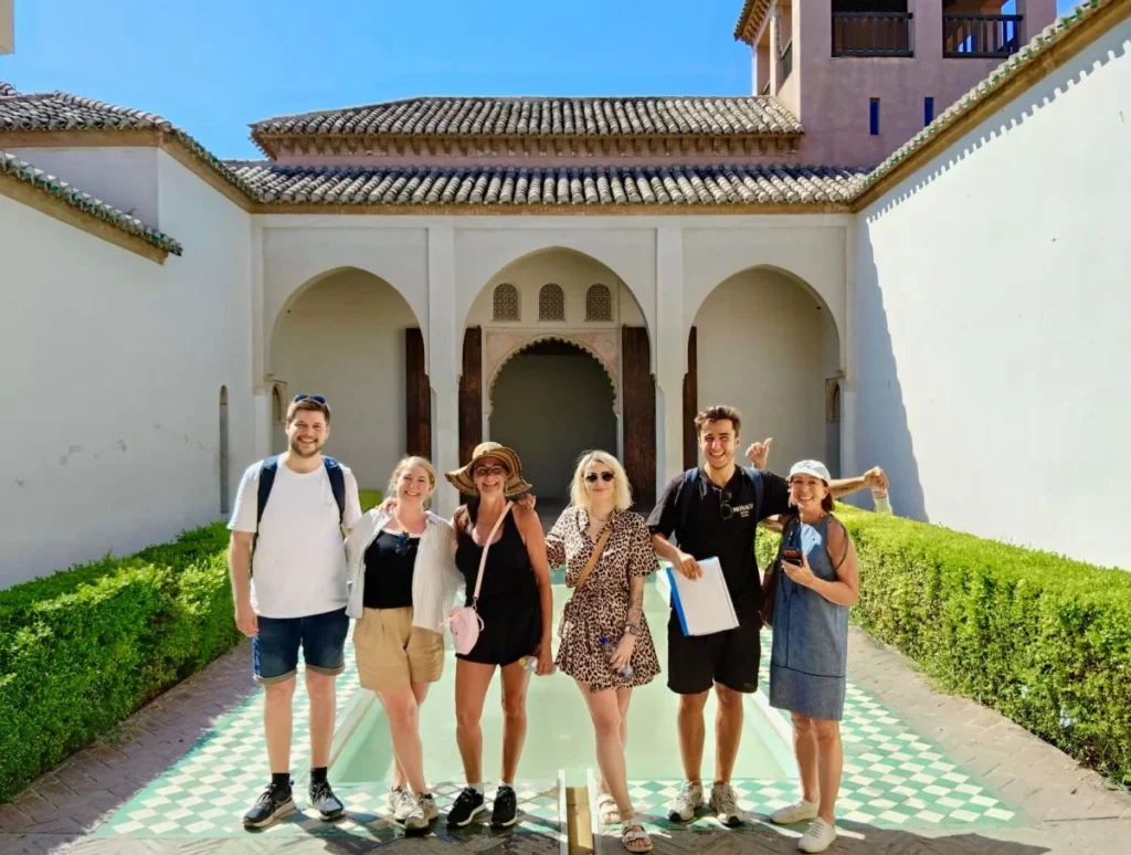 Inside Málaga's moorish fortress Alcazaba during a free tour with a guide and tourists having fun with the pool and palace in the background