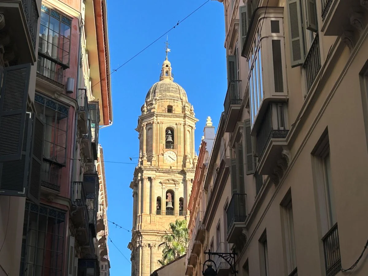 Málaga Cathedral bell tower framed between old town buildings on a narrow historic centre street