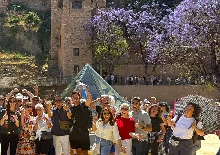 Guided free walking tour group alcazaba and roman theatre Málaga with tour guide and purple trees